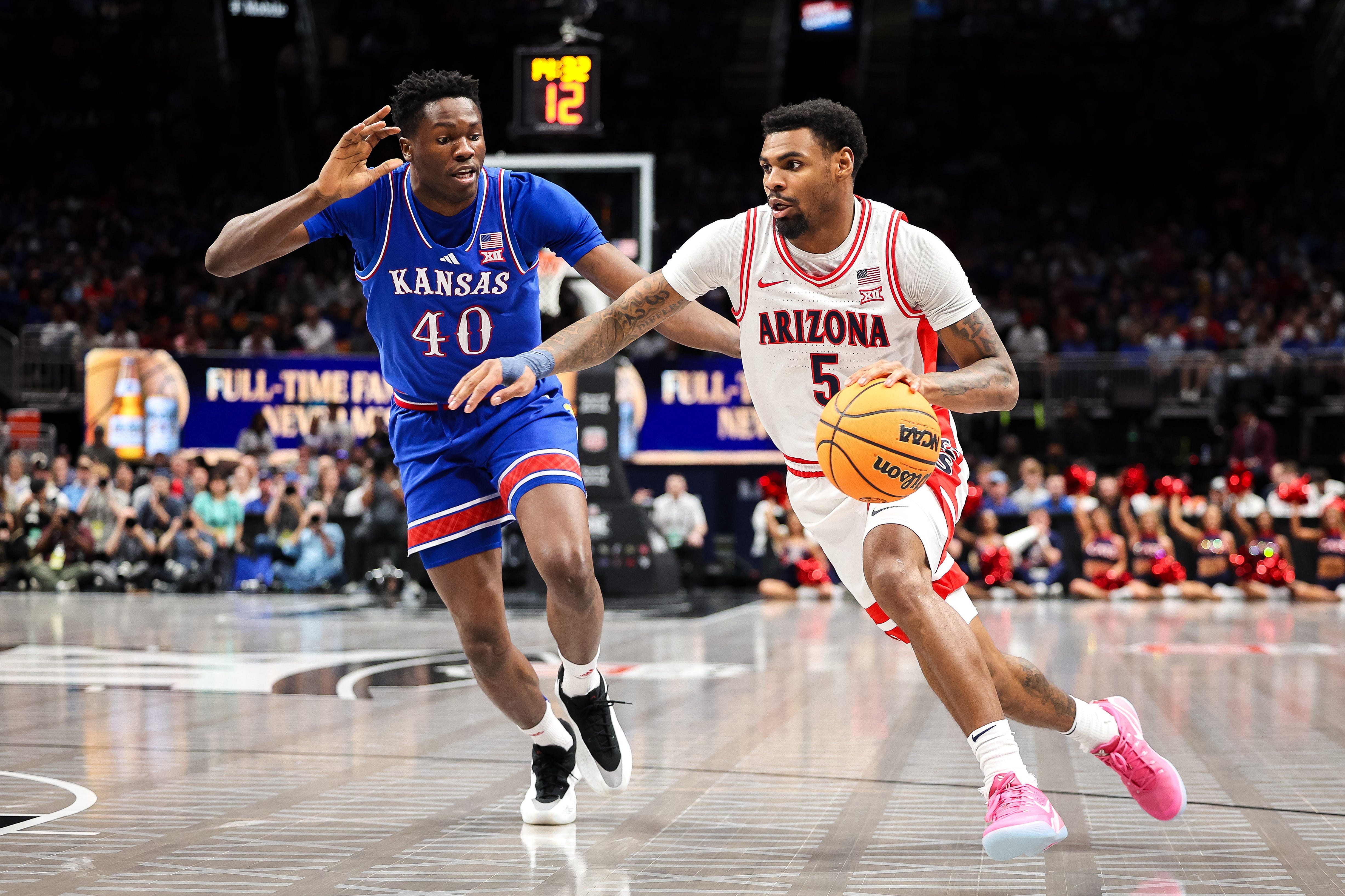 Mar 13, 2025; Kansas City, MO, USA; Arizona Wildcats guard KJ Lewis (5) drives to the basket around Kansas Jayhawks forward Flory Bidunga (40) during the first half at T-Mobile Center. Mandatory Credit: William Purnell-Imagn Images