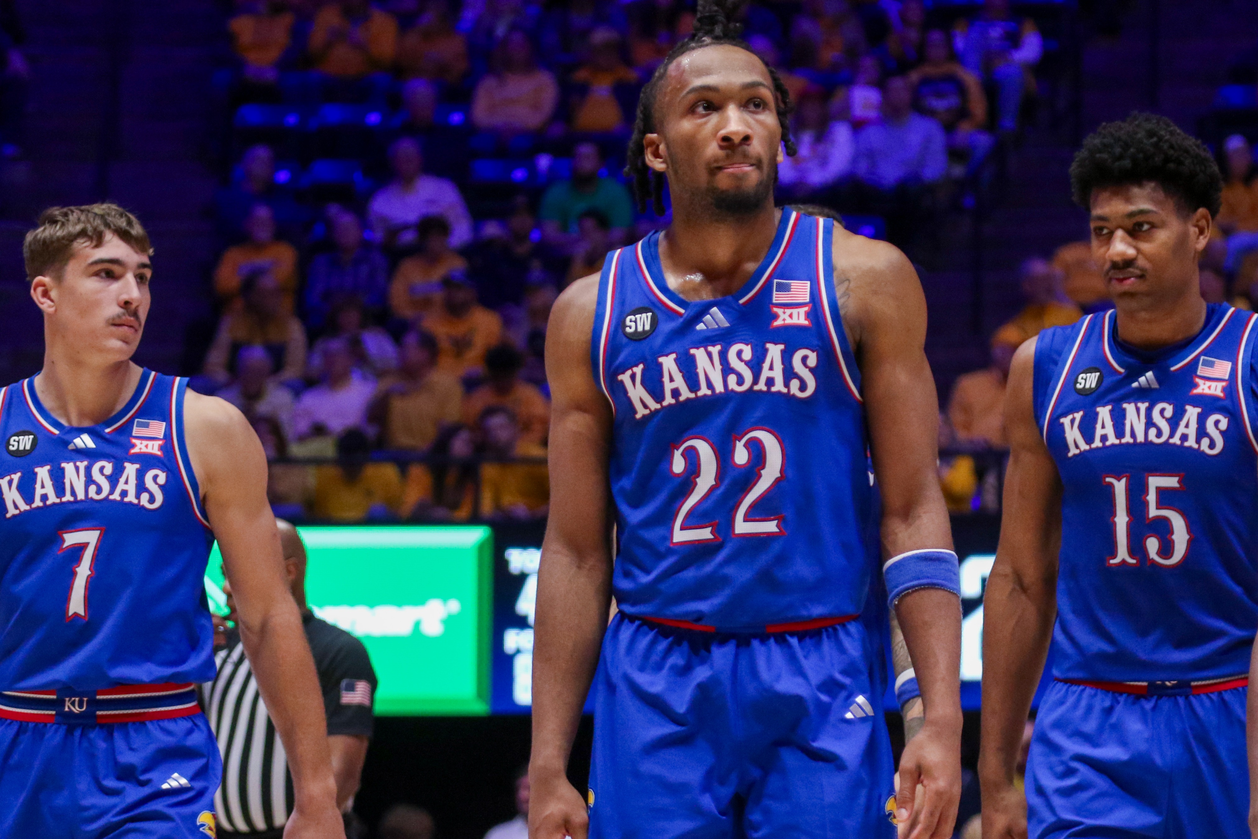 Four Kansas basketball players in blue uniforms standing on the court.
