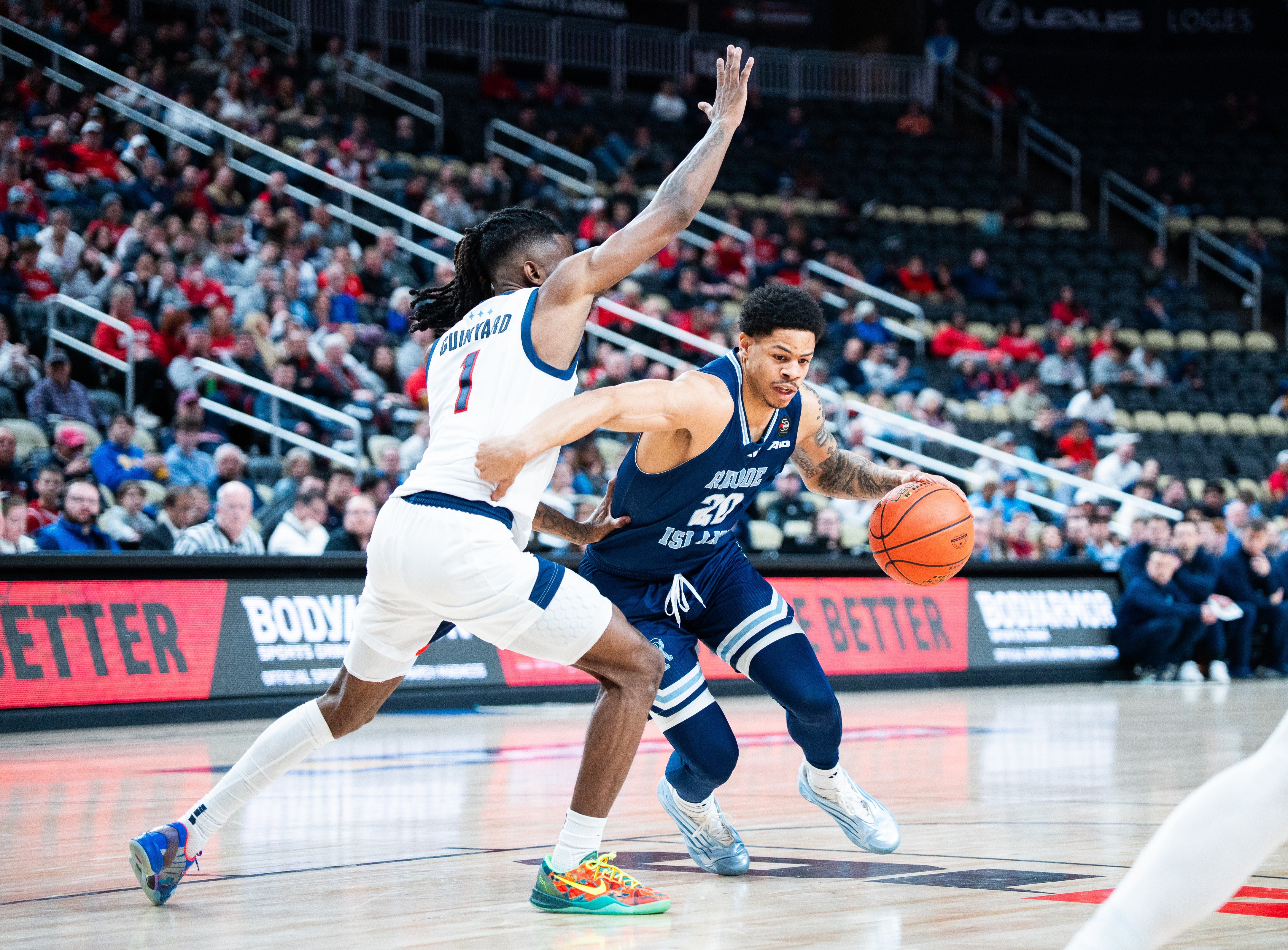 Myles Corey (20) of URI, right, fights to get past the defense of Duquesne's Tarence Guinyard (1) at Atlantic 10 Tournament in Pittsburgh.