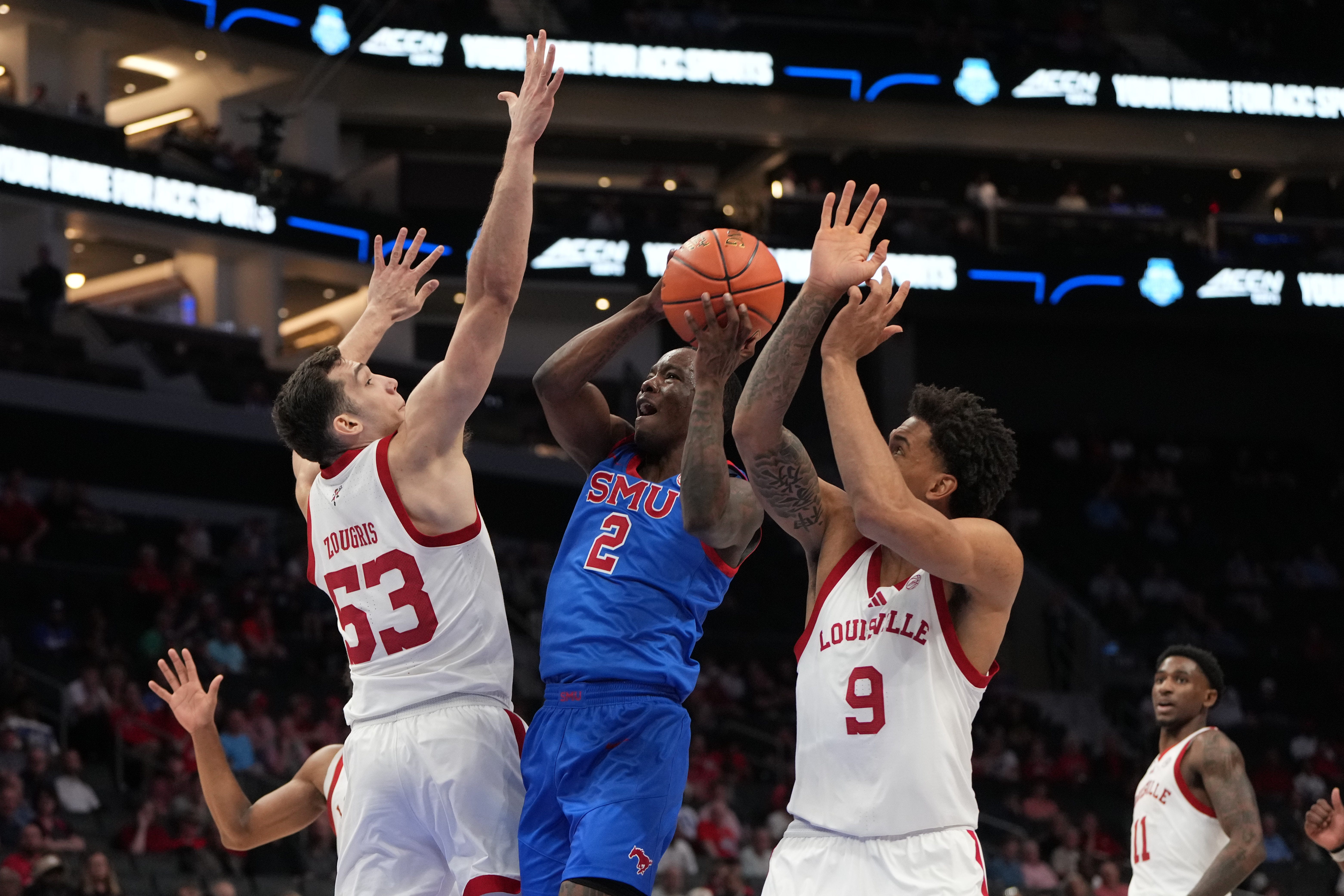 Mar 11, 2026; Charlotte, NC, USA; Southern Methodist University Mustangs guard Boopie Miller (2) drives as Louisville Cardinals forward Vangelis Zougris (53) and forward Khani Rooths (9) defend in the first half at Spectrum Center. Mandatory Credit: Bob Donnan-Imagn Images