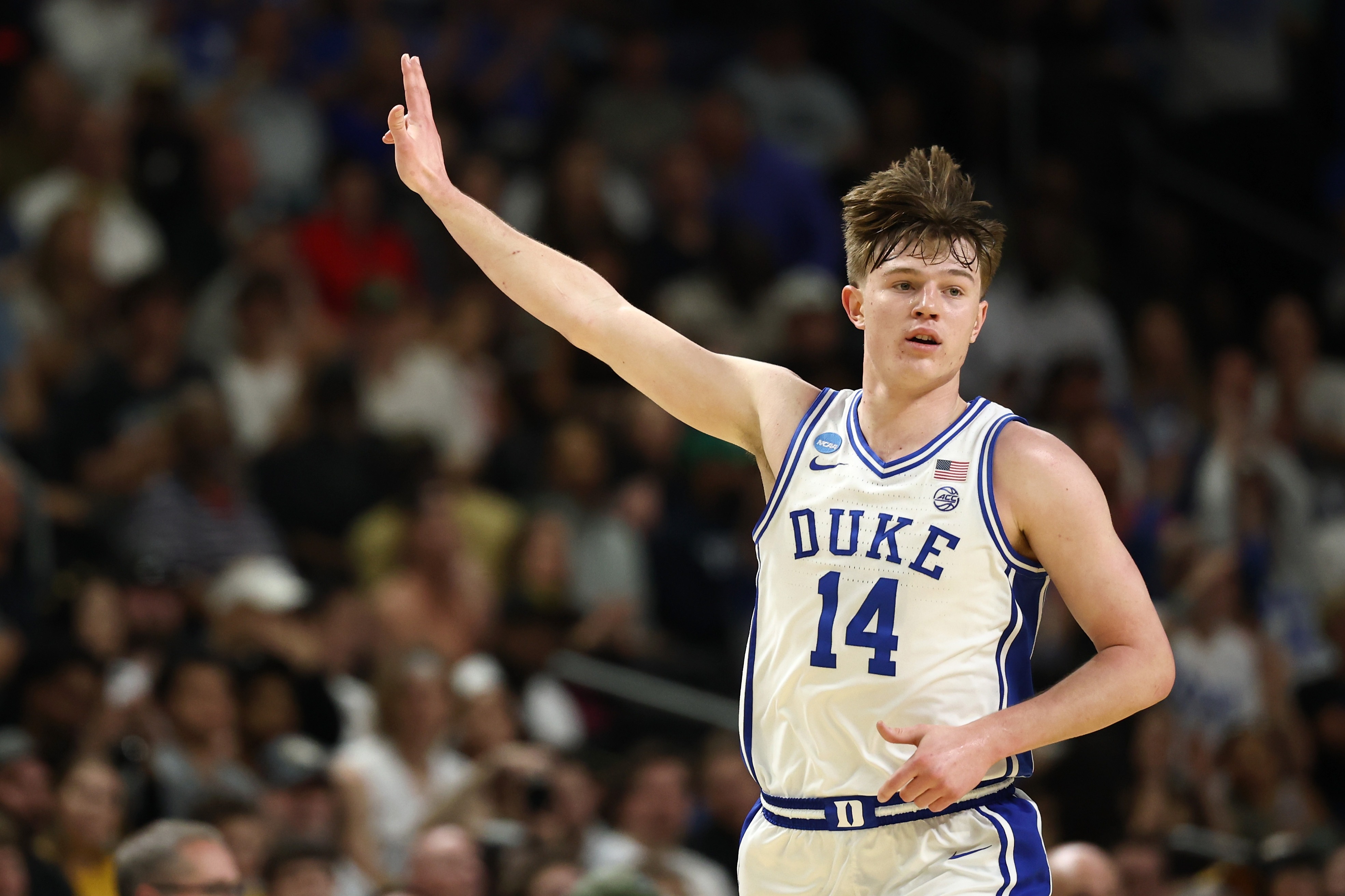 Duke basketball player Nikolas Khamenia in a white and blue uniform with his arm raised.