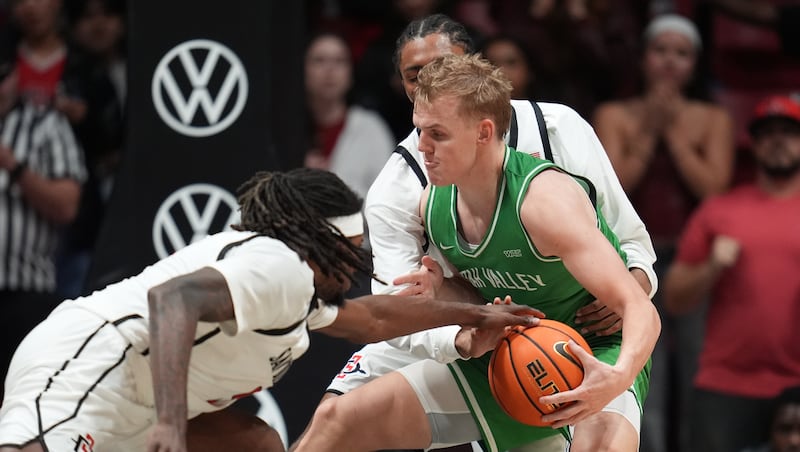 Utah Valley guard Jackson Holcombe, center, tries to hold on to the ball as San Diego State forward Pharaoh Compton, front, and guard Taj DeGourville, behind, defend during the second half of an NCAA college basketball game Wednesday, Dec. 3, 2025, in San Diego.
